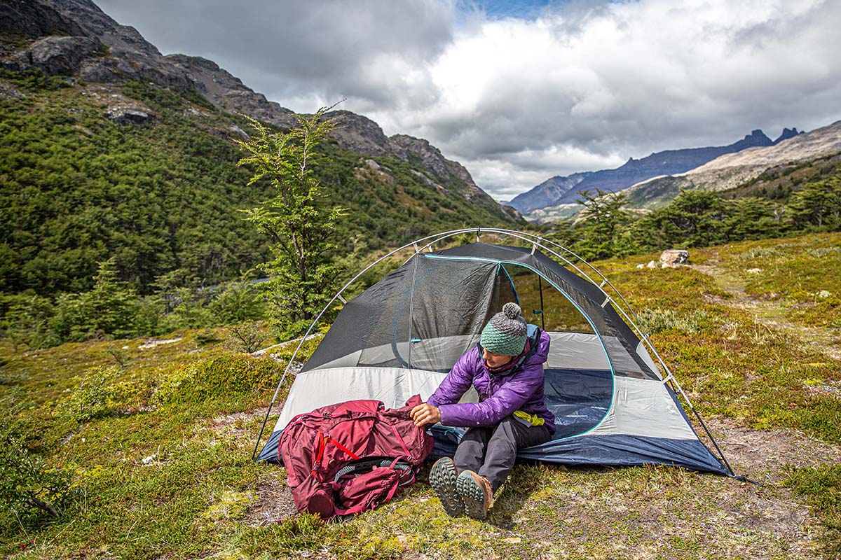 Reaching into pack beside tent (Osprey Aura AG LT 65 women's backpacking pack)